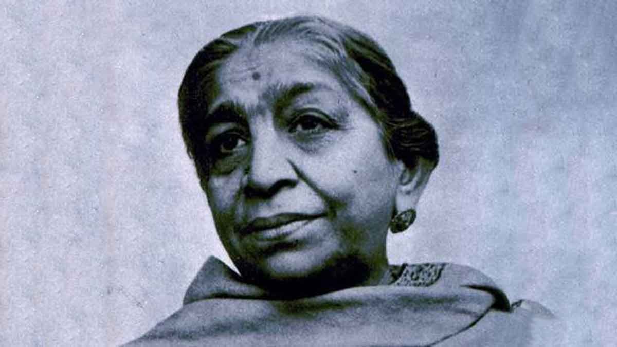 Blue-toned photographic portrait of Sarojini Naidu in later life, wearing a shawl drawn over her shoulders.